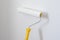Paint roller with yellow handle. Ceiling and wall painting process. White background. Copy space