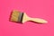 Paint varnishing brush with wooden handle varnish on trendy fuchsia pink background. Interior design home refurbishing fashion