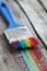 Paintbrush and multicolor rainbow brush strokes on wooden plank.