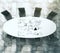 Painted business scheme on oval white conference table with black leather chairs on concrete floor