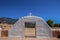 Painted doorway topped by cross with mountains and blue sky and man carrying bucket viewed through it at Taos Pueblo in New Mexico