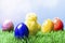 Painted easter eggs and a chicken in grass, blue background