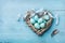 Painted Easter eggs in heart nest on vintage turquoise background top view in flat lay style.