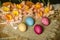 Painted Easter eggs and large pink daffodils with biscuits,lie on a straw carpet