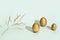 Painted Easter shiny eggs and gold colored plant on light green paper. Minimal easter concept. Spring holiday background