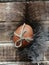 A painted egg tied with a jute rope, the concept of an Easter gift, lies on a feather on a brown wooden background