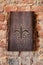 Painted Fleur de Lis on natural wooden slab against an old exposed brick wall