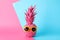Painted pink pineapple with sunglasses on two tone background