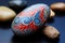 a painted rock with red and blue leaves