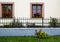 Painted windows with geraniums and fence with a flower bed