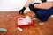 Painter with black gloves pours red color pigment for painting wall of room from bottle into bowl for paint mixing.