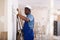 Painter in blue overalls leveling plaster on the wall with spatula