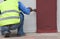 Painter hand with brush brown paint on concrete wall