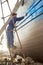 Painter painting a ship with spraying paint, Essaouira port, Morocco