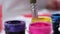 Painter puts down brush in jar of yellow gouache paint, standing on table with other colored paints on background of