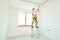 Painter in stilts with putty knife. Plasterer smoothing ceiling surface at home renewal