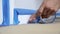 Painter Using Masking Blue Tape to Secure Baseboard, Moulding. Preparation For Room Painting