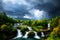 painterly image of the dramatic storm clouds at the waterfall area.