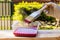 Painting brush in a woman`s hand for painting a wooden surface with a plastic container for paint. Gardening outdoors.