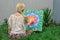 Painting outdoors, a young woman blonde draws a mandala on the nature sitting in the grass