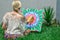 Painting outdoors, a young woman blonde draws a mandala on the nature sitting in the grass