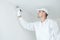 Painting. Painter with paint brush covering ceiling angle with white paint