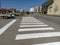 Painting pedestrian crossings with new paint. Road warning plastic orange cone. Street with houses, people and cars