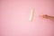 Painting and renovation. A hand holding a paint roller against the pink background newly painted. Soft focus on the laborpi`s hand