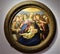 Painting with a round frame, depicting Madonna with baby Jesus in her arms and other children around, at the Uffizi museum in Flor