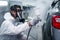 Painting tool in hand of mechanic man painter wearing chemical protective mask while working with auto mechanic painting a car,