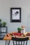 Painting on a wall and dining table with apples, tomatoes and wooden utensils in a dining room interior