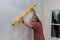 Before painting a wall of drywall, an employee makes sure that it is level by using a level