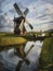 A painting of a windmill in a dutch landscape.