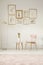 Paintings in golden frames, pink chair, table and lamp set on th