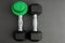 Pair of 15-pound dumbbells on a black gym floor, green leprechaun hat