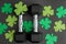 Pair of 15-pound dumbbells on a black gym floor, green shamrocks