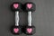 Pair of 15-pound dumbbells on a black gym floor, pink sparkly hearts