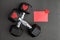 Pair of 15-pound dumbbells on a black gym floor, red sparkly hearts, red note card