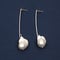 Pair of baroque pearl silver earrings on dark blue background