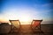 Pair of beach loungers on the deserted coast sea at sunrise