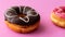 Pair of black and pink donuts on colorful pink backgrou