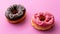 Pair of black and pink donuts on colorful pink backgrou