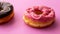 Pair of black and pink donuts isolated on colorful pink background