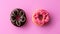 Pair of black and pink donuts isolated on colorful pink background