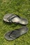 A pair of black rubber flip-flops on the green lawn grass with a copy of the space, summer, outdoor, top view, vertical
