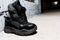 Pair of black sneakers with thick soles on the cement floor against the background of white wall