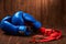 Pair of blue boxing gloves with two rolls of hand bandage on wooden background.