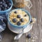 Pair of blue ceramic bowls full breakfast cereal with fresh blueberries and milk