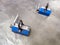 Pair of blue industrial lifting magnets on flat sheet metal surface.