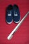 Pair of blue sneakers and shoe horn on red background